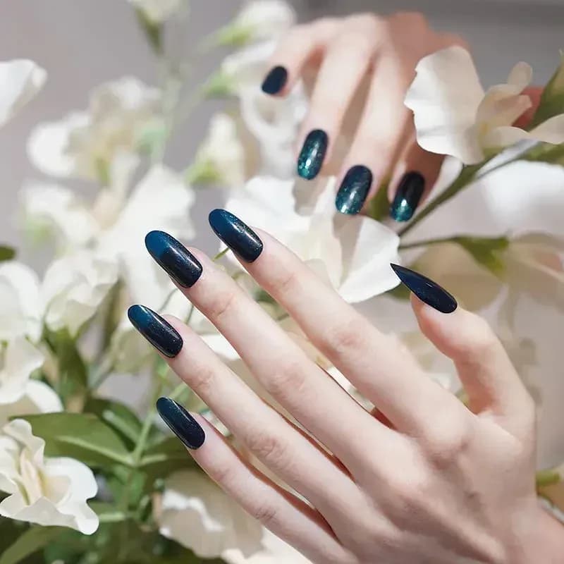 Emerald Twinkle dark green glitter gel nails held among white flowers