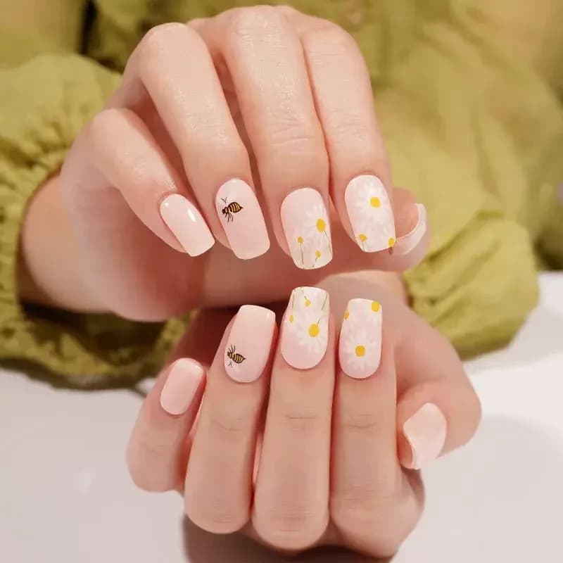 Honey Bee blush gel nails with white daisies and tiny bees, shown on both hands