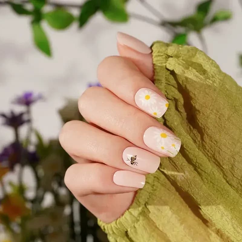 Honey Bee daisy and bee gel nails against a sage green sleeve