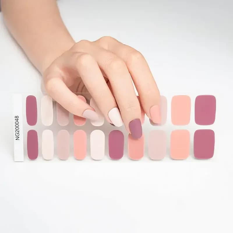 Neutral Harmony gel nail strips, the mixed mauve, peach and cream 20-strip sheet under a hand