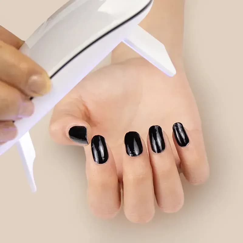 Curing Noir Nights black gel nail strips under an LED UV lamp