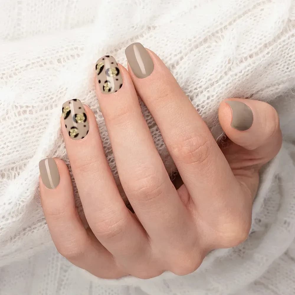 Nude Safari taupe and leopard print gel nails against a cream knit jumper
