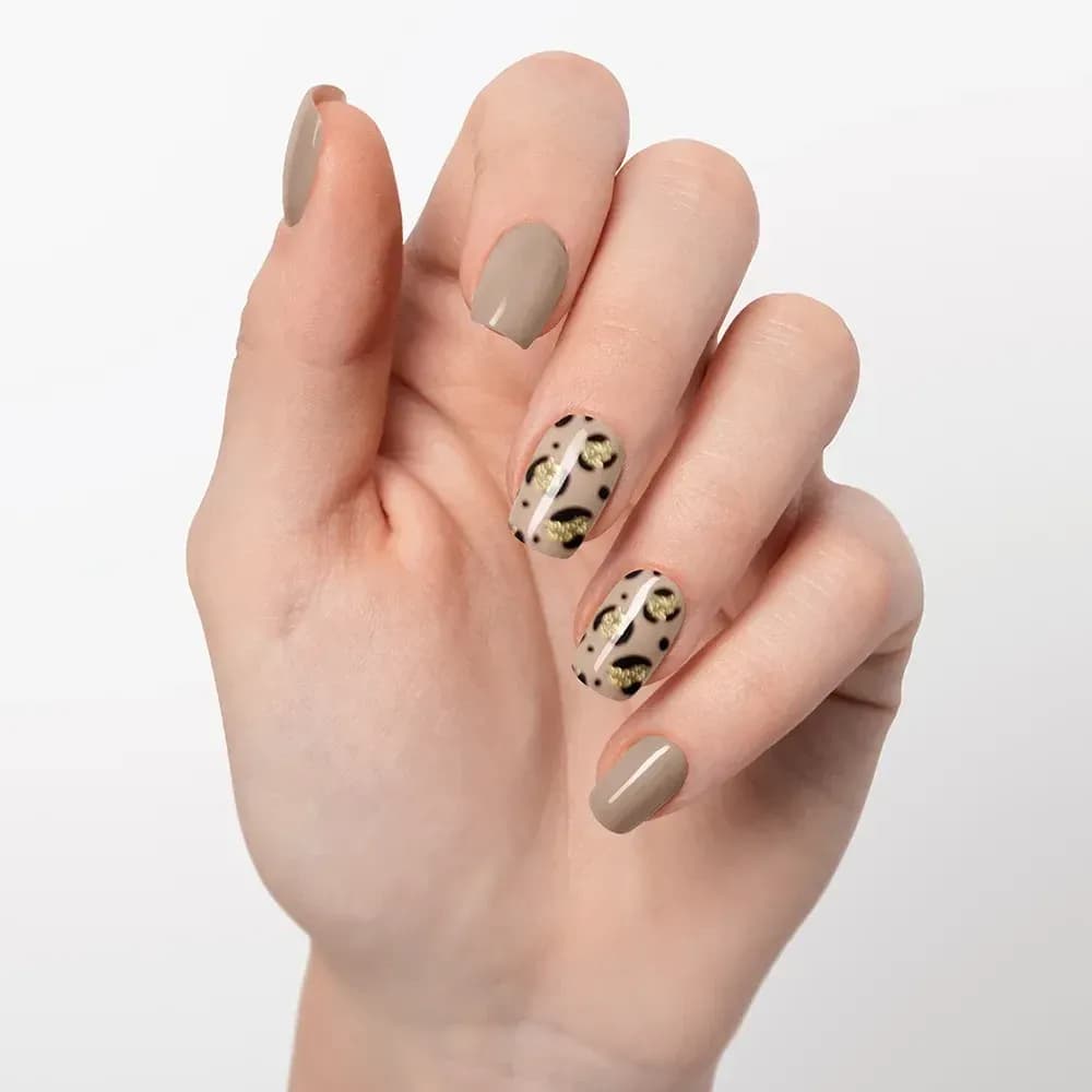 Nude Safari taupe gel nails with leopard accents, shown on a raised hand
