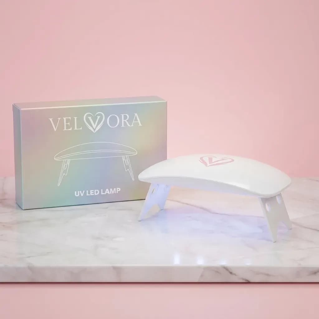 Velvora pink UV LED nail lamp with its holographic box on a marble shelf