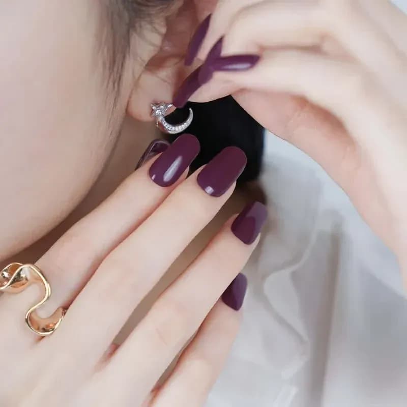 Royal Plum deep plum gel nails, close up with a crescent moon earring