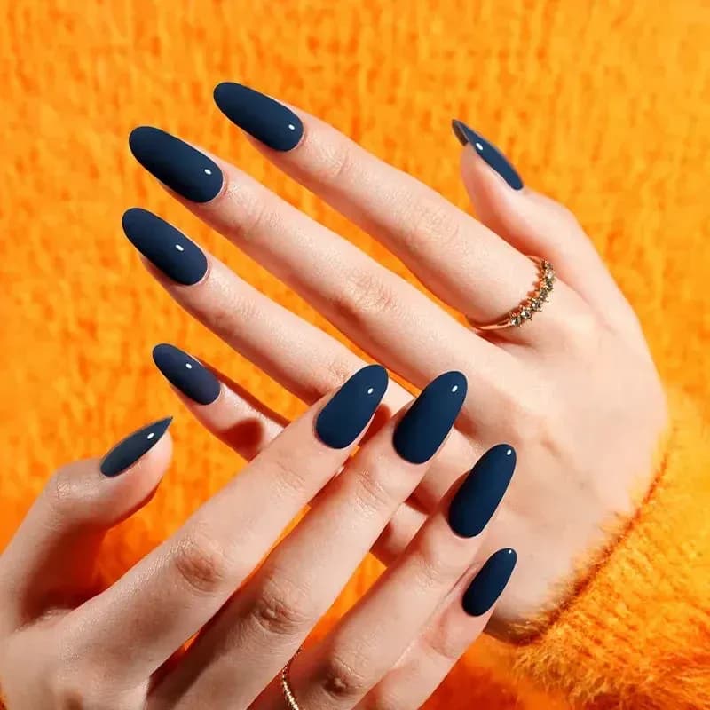 Teal of Approval deep teal gel nails on almond nails against an orange jumper