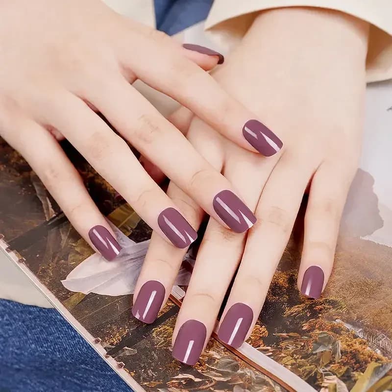 Vintage Rose dusty mauve gel nails on both hands resting on a magazine