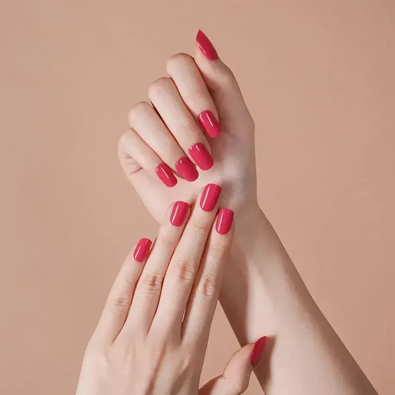 Wild Orchid raspberry pink gel nails on crossed hands against a peach background