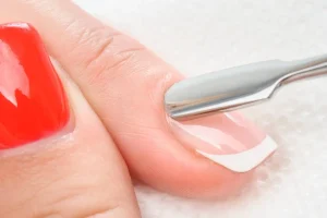 Close-up of a cuticle being gently pushed back with a metal tool during a manicure