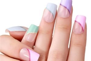 Hand with pastel gel nail strips in pink, purple, mint and blue with glitter accents