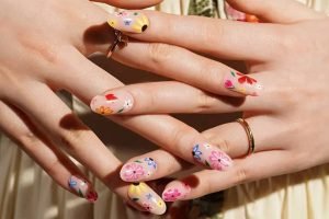 Hands with colourful summer floral gel nail strips on almond-shaped nails