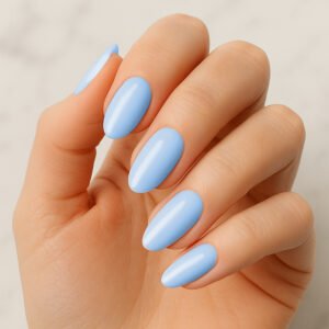 Hand with almond-shaped nails wearing glossy sky blue semi-cured gel nail strips – soft pastel manicure for a fresh, airy at-home nail look.
