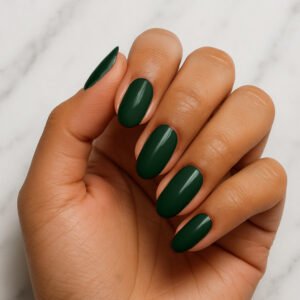 Hand with almond-shaped nails wearing deep jungle green semi-cured gel nail strips – glossy forest-toned manicure for a bold, moody at-home nail look.