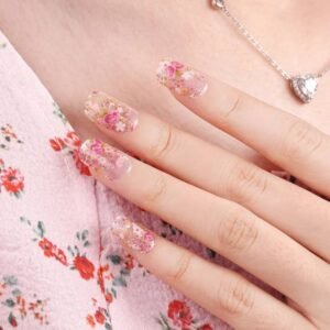 Hand wearing Blooming floral gel nail strips touching neckline with heart pendant.