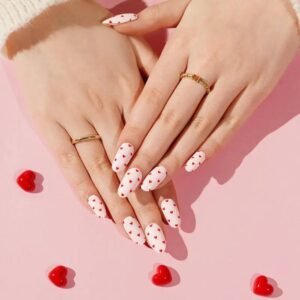 Both hands with Velvora Love Hearts heart-print nail wraps on pink backdrop.