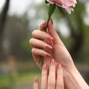 Velvora Love Script gel nail wraps holding a pink rose – blush nails with white heart script, glossy finish