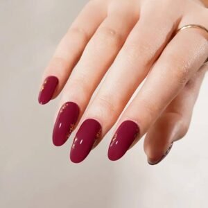 Side view of Velvora Royal Rose nails: burgundy gel with scattered gold-foil flakes.
