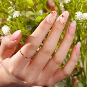 Close-up of Velvora Strawberry Fields nails: blush-pink base with daisies and tiny strawberries.